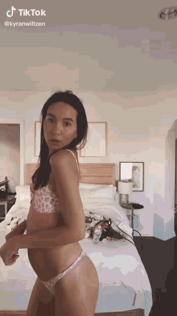 a woman in a bikini is dancing in a bedroom .