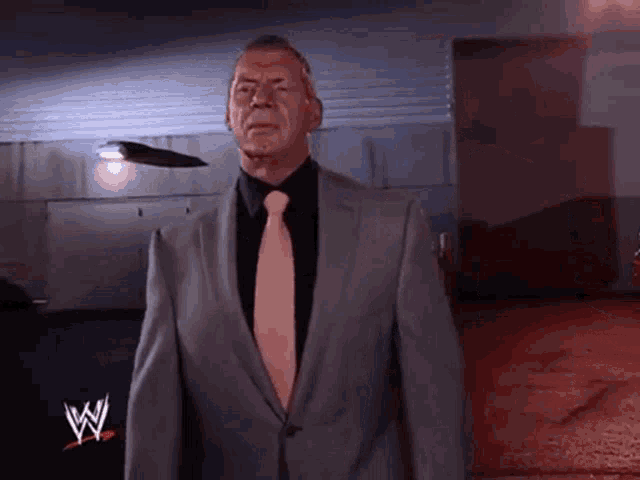 a man in a suit and tie with a w logo on his chest