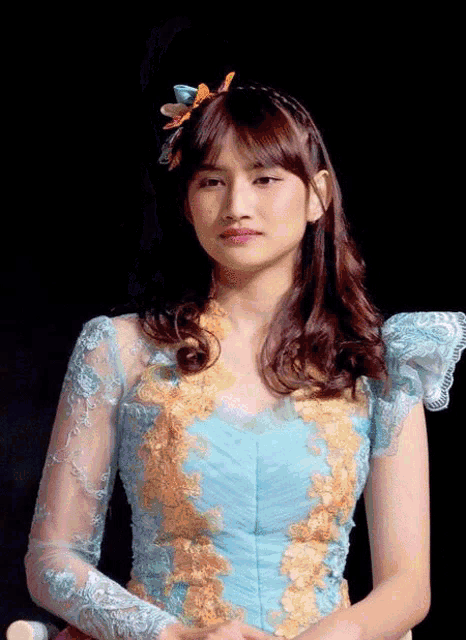 a girl in a blue and gold dress with a flower in her hair