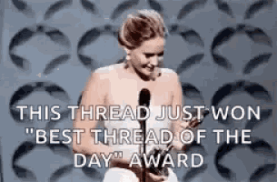 a naked woman is holding a trophy in front of a microphone and saying this thread just won " best thread of the day " award