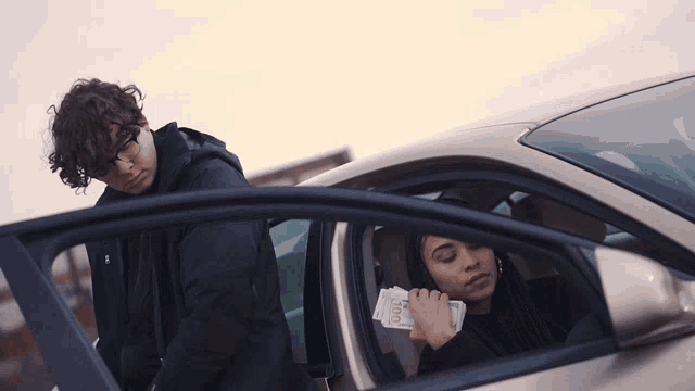 a woman sitting in a car holding a stack of 100 bills