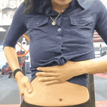a woman in a blue shirt holds her stomach in front of a sign that says push