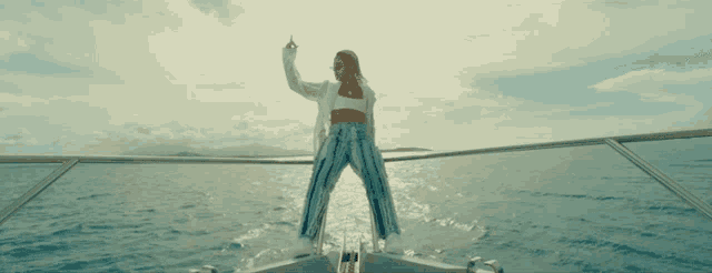 a woman is standing on the back of a boat in the water