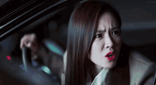a woman with red lips is making a funny face while driving a car