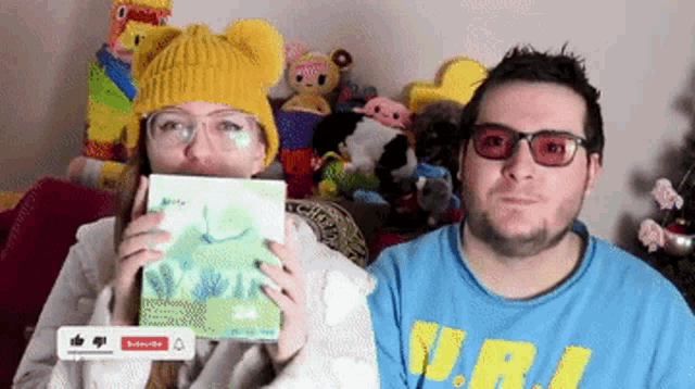 a man and a woman are holding a book in front of a subscribe button on a screen