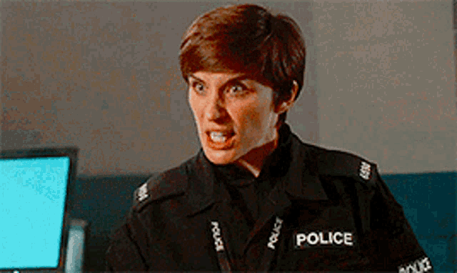 a woman in a police uniform is making a funny face while standing in front of a computer .