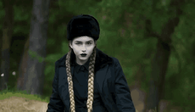 a woman wearing a black jacket and a black hat is standing in a field .