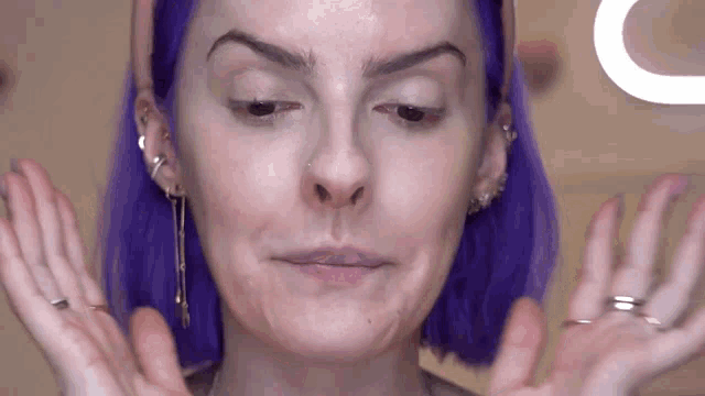 a woman with purple hair is making a face
