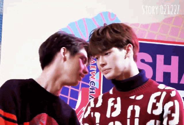 two men are standing next to each other and one has a sweater that says aew cha