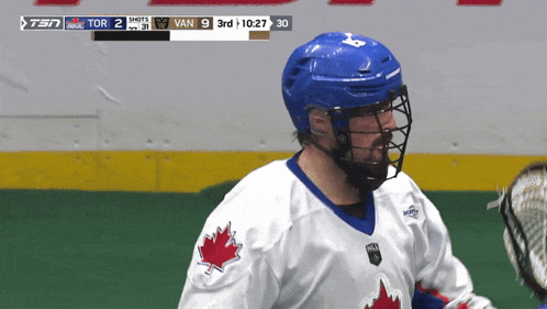 a hockey player wearing a blue helmet and a white jersey with a maple leaf on the shoulder