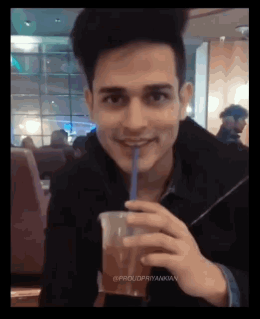 a young man drinking from a plastic cup with a straw in his mouth ..