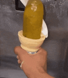 a person is holding an ice cream cone that has a pickle in it .