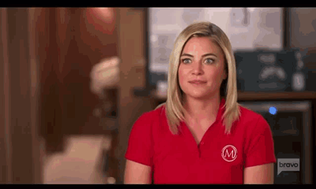 a woman wearing a red shirt with the letter m on it is sitting in a room .