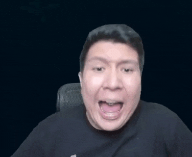 a man in a black shirt is sitting in a chair with his mouth open .