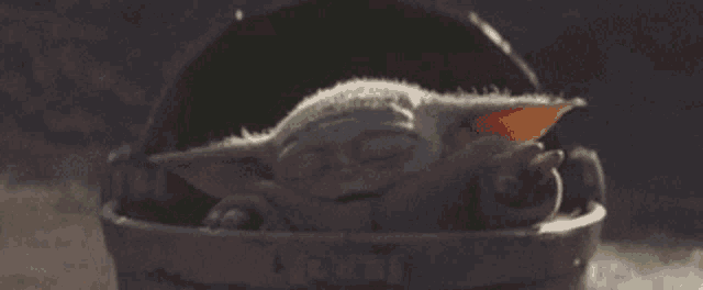 a baby yoda is sleeping in a bucket with a green line .