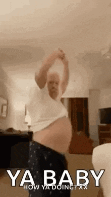 a pregnant man is dancing in a living room with his arms outstretched .