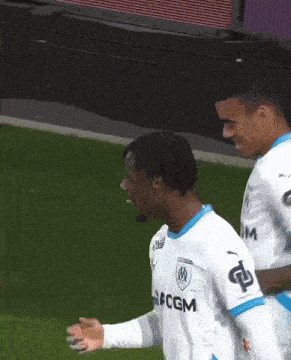 a soccer player wearing a cgm jersey celebrates a goal with his teammate