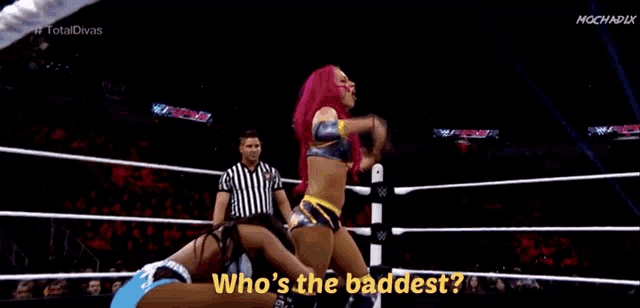 a woman with pink hair is standing in a wrestling ring with a referee .