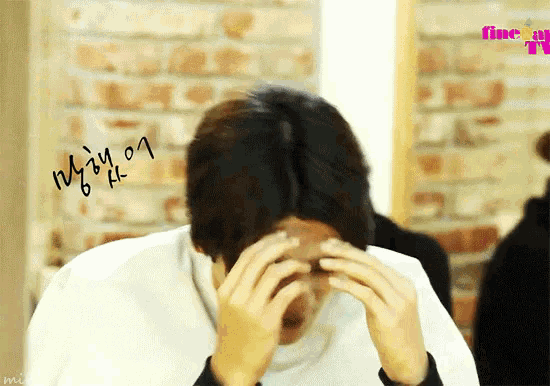 a person covering their face with their hands in front of a brick wall with the word fine on the bottom