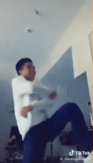 a man in a white shirt is dancing in a room with a tiktok watermark
