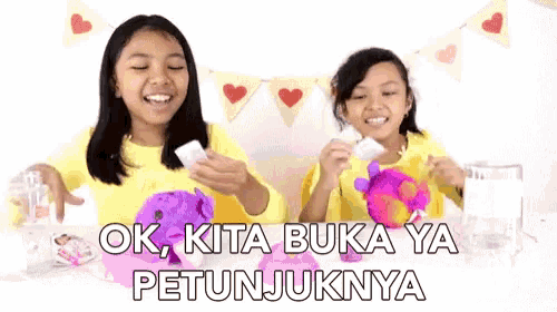 two girls are playing with a stuffed animal and the words ok kita buka ya petunjuknya are on the bottom
