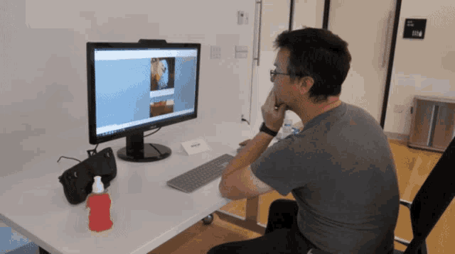 a man sitting at a desk looking at a computer monitor