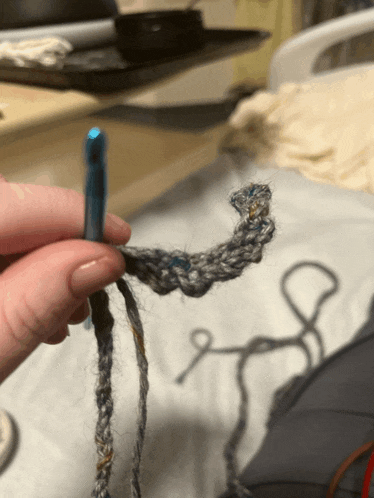 a person is holding a blue crochet hook