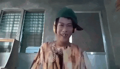 a young boy wearing a green hat and headphones is standing in front of a window .