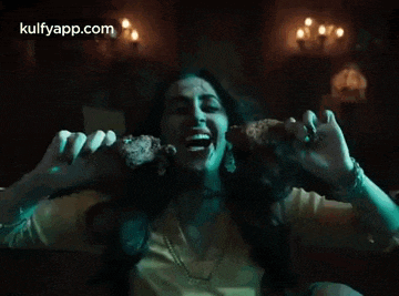 a woman is eating a piece of meat in a dark room while screaming .