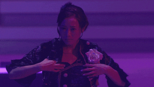 a woman in a black dress is standing on a stage in front of a crowd