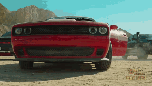 a red dodge challenger is parked in a desert
