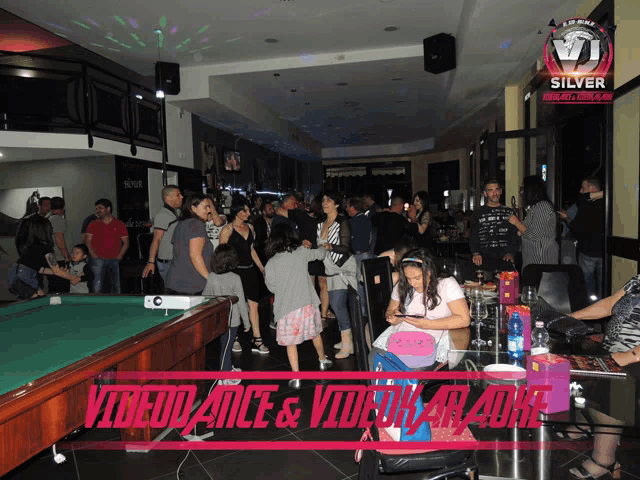 a group of people are gathered in front of a pool table and a sign that says silver