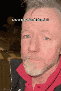 a man with a beard is wearing a red shirt and a black jacket and says nouvelle quetes debloque