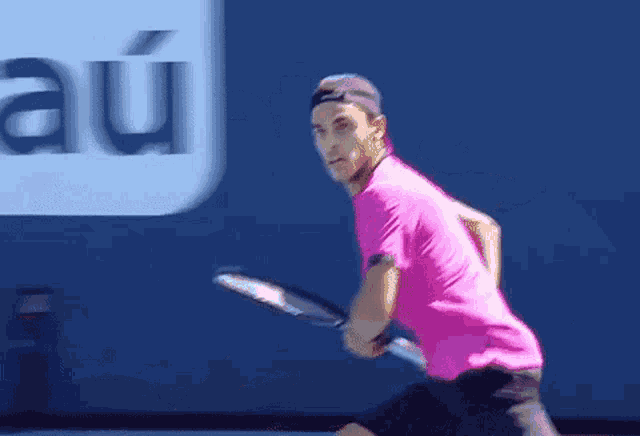 a man in a pink shirt is swinging a tennis racket