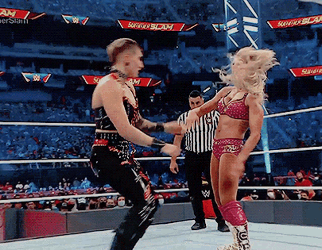 a woman in a bikini is standing next to a man in a wrestling ring with a banner that says summerslam