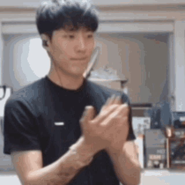 a man in a black t-shirt is clapping his hands .