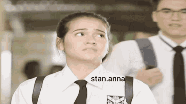 a girl wearing a white shirt and black tie has stan.anna written on the front of her shirt