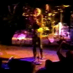a blurred image of a man playing a guitar on a stage