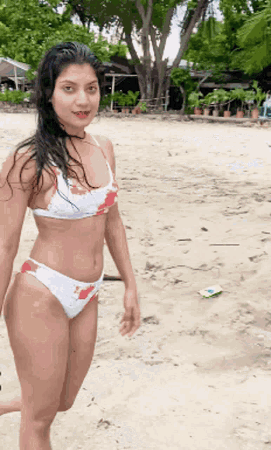 a woman in a bikini stands on a beach