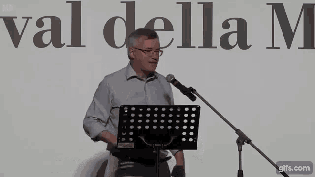 a man is standing in front of a microphone with the words andiamo a bruciargli la casa written below him