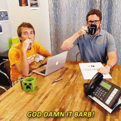 two men are sitting at a table with a laptop and a phone with the words god damn it barb written on it