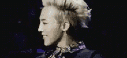 a man with white hair and a purple shirt is covering his face with his hands .