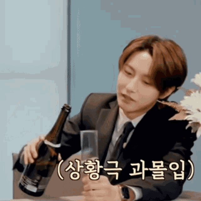 a man in a suit is holding a bottle of wine and a glass .