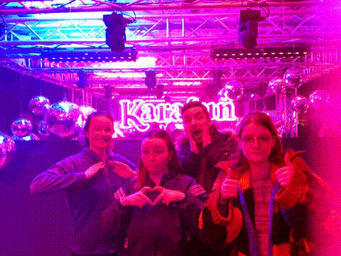 a group of people are posing for a photo in front of a sign that says karamin