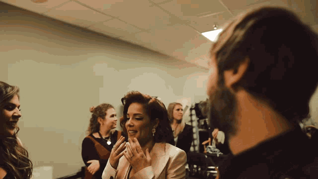 a group of people are standing in a room talking to one another