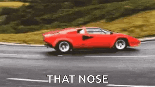 a red sports car is driving down a road with the words `` that nose '' .