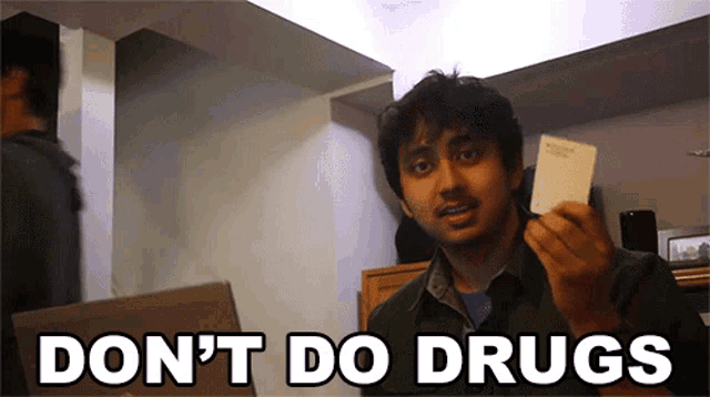 a man holding a card with the words " do n't do drugs " above him