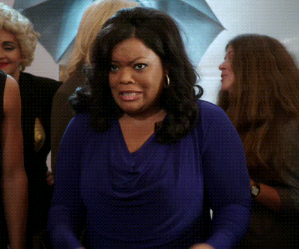 a woman in a purple shirt is making a funny face
