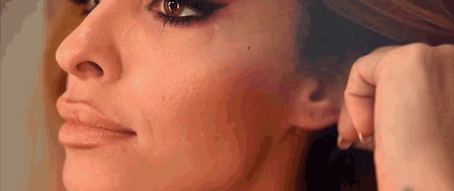 a close up of a woman 's face with a tattoo on her arm