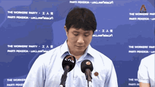a man stands in front of two microphones with cna written on them